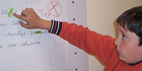 Kind zeigt auf einen Buchstaben auf einem Flipchart